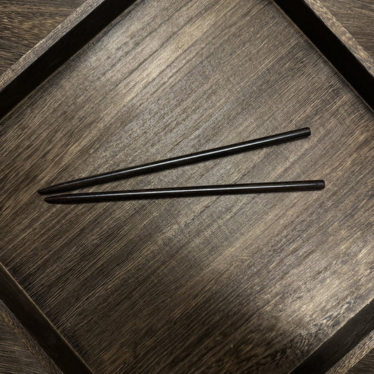 Pair of natural African Blackwood hair sticks with chopstick (kuai niang) design 18cm on wooden tray.