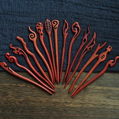 Set of natural red sandalwood 18cm hair sticks with assorted carved designs arranged on blue fabric background
