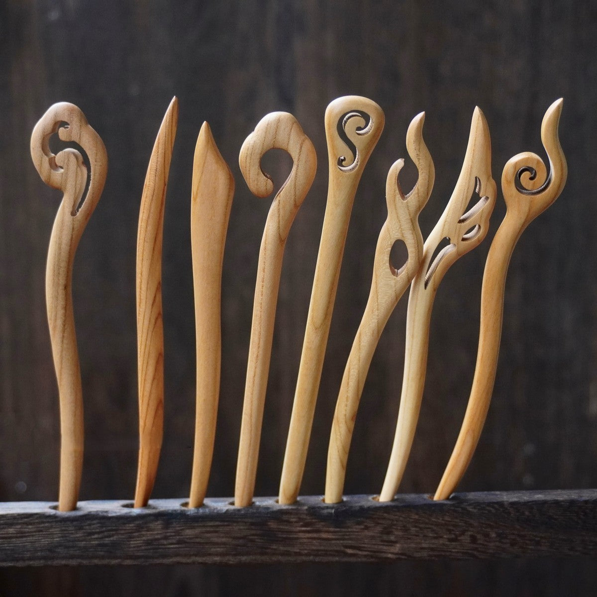 Set of natural peach wood 15cm hair sticks with assorted abstract swirl and flame designs on dark background