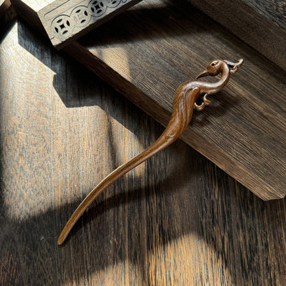 Natural lacewood 19cm hair stick with vermilion bird design on dark wooden surface