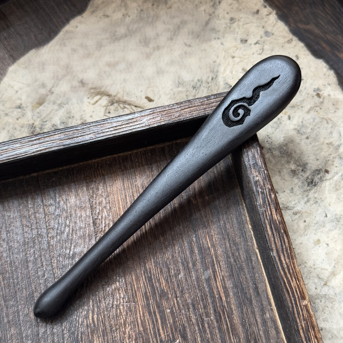 Natural African blackwood hair stick with Lihuo flame carving displayed on wooden tray