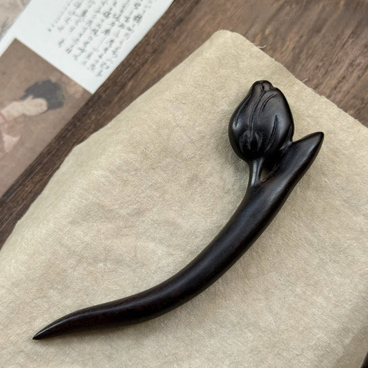 Natural African Blackwood hair stick with tulip flower design 12cm on textured fabric background.