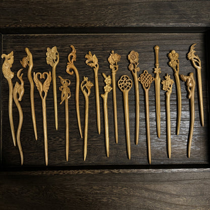 Set of natural aged peach wood hair sticks with assorted floral and nature carvings arranged in wooden tray