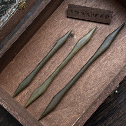 Three green sandalwood hair sticks in the double-pointed Emei Piercer style, arranged neatly inside a dark wooden box.