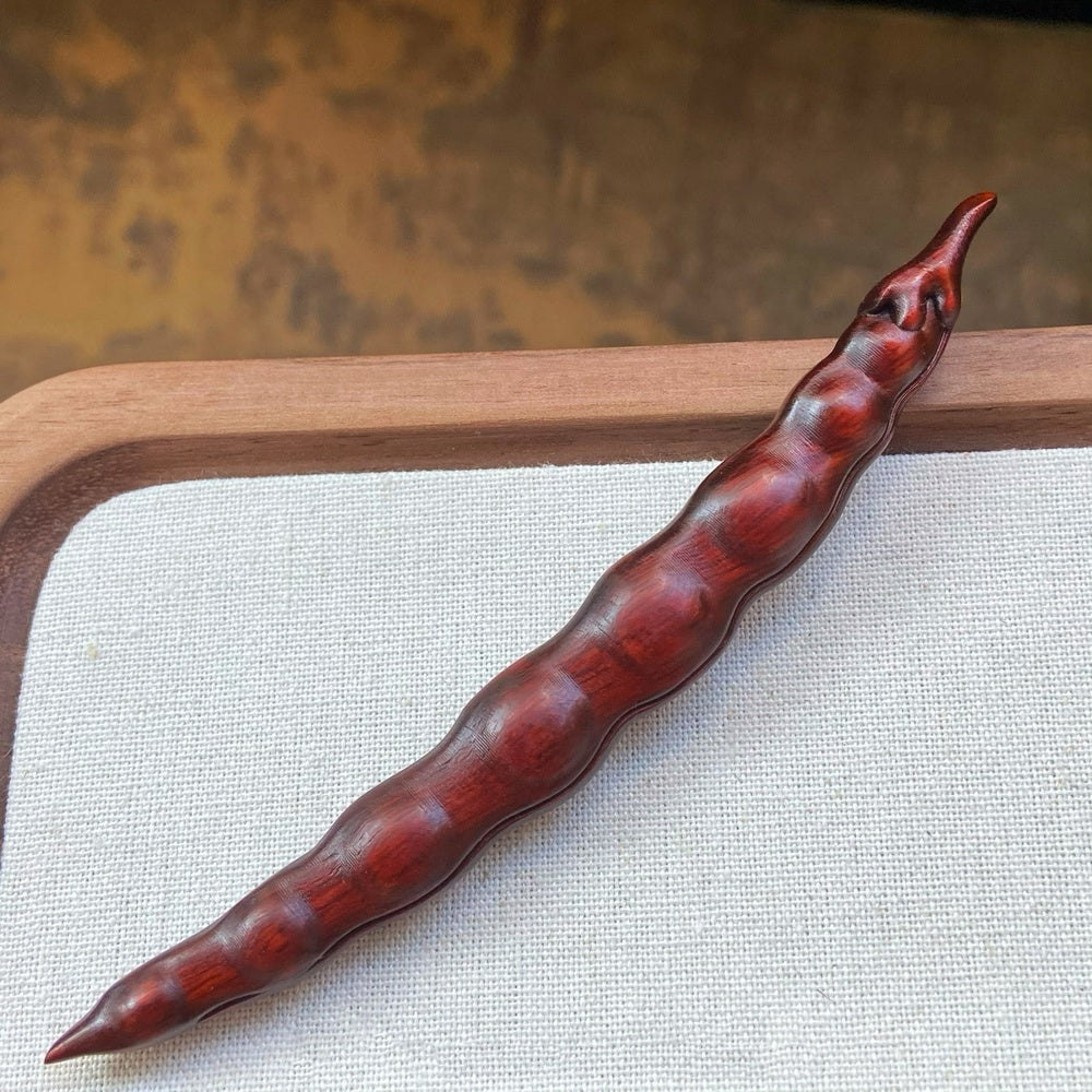Close-up of red rosewood handcrafted hair stick with natural texture