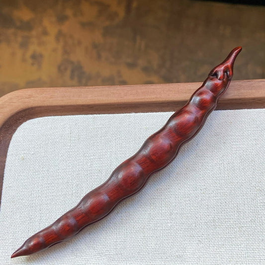 Close-up of red rosewood handcrafted hair stick with natural texture