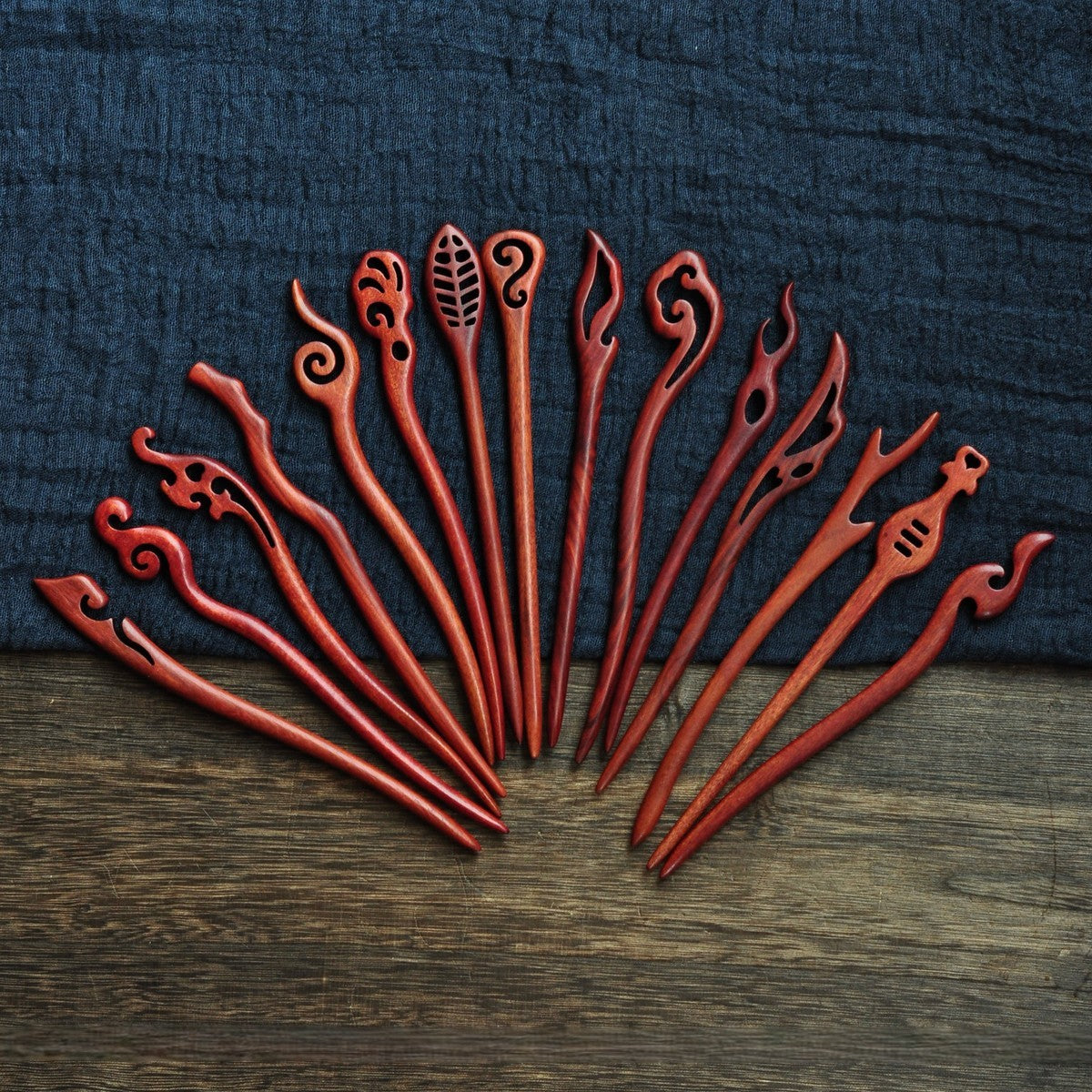 Collection of polished red sandalwood hairpins featuring flame, cloud, leaf, and swirl motifs in deep red tone