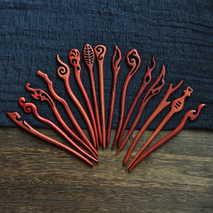 Collection of polished red sandalwood hairpins featuring flame, cloud, leaf, and swirl motifs in deep red tone