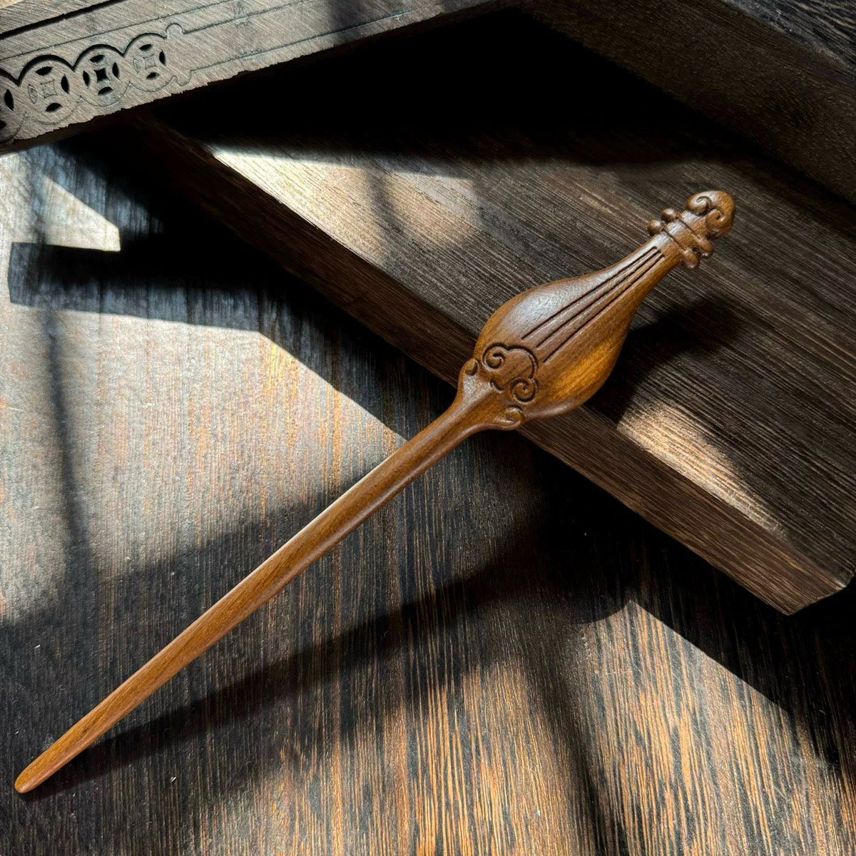 A hand-carved Tatajuba wood hairpin with a pipa (lute) shaped top and engraved cloud details.