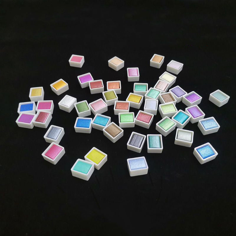 Full set of metallic pearlescent solid watercolor paint pans in assorted vibrant colors, displayed in clear cases.