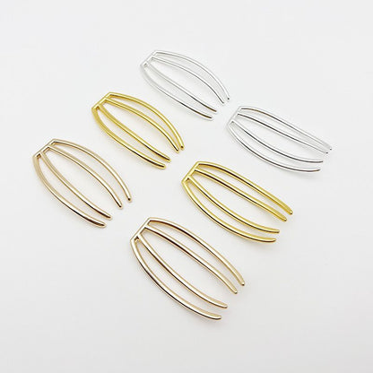 An assortment of four-prong metal hair forks in both gold and silver finishes, used as craft supplies.