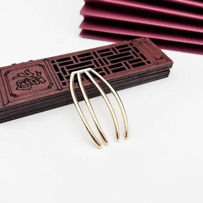 Close-up of a gold four-prong hair fork component, showing its smooth and high-quality finish.
