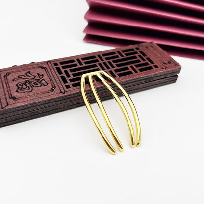 A minimalist four-prong hair fork in a polished gold finish, ideal for DIY projects.