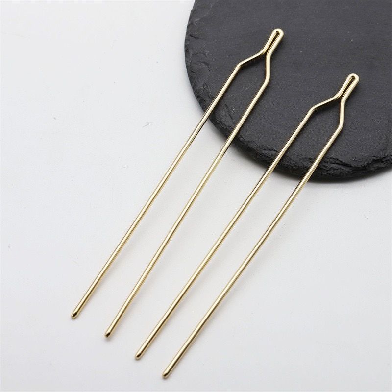 Close-up view of the minimalist Y-shaped top of a gold metal hair stick finding.