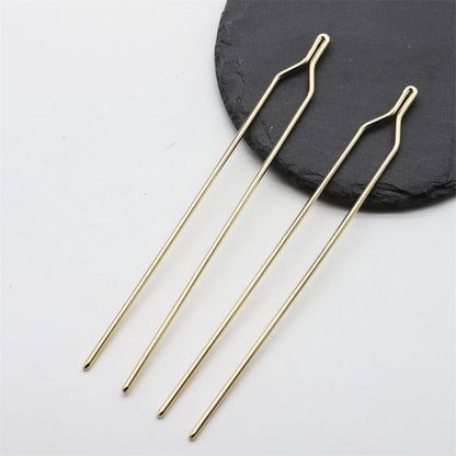Close-up view of the minimalist Y-shaped top of a gold metal hair stick finding.