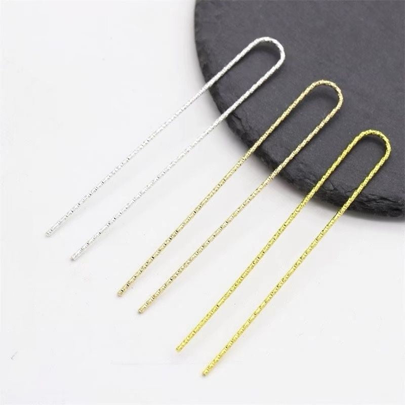 A set of U-shaped hair fork craft supplies in silver, light gold, and yellow gold finishes, displayed on a dark slate.
