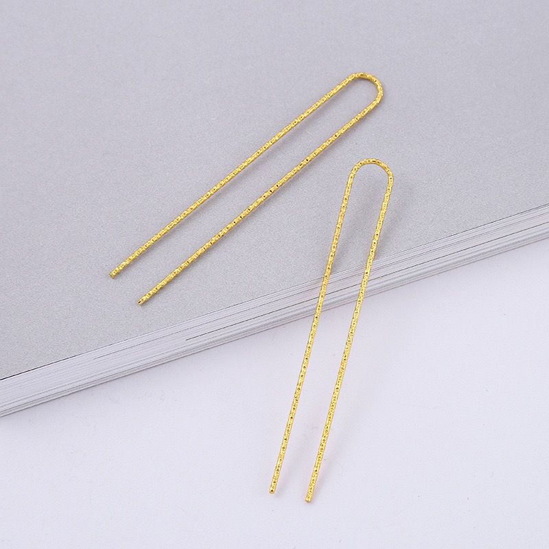 A pair of 75mm gold-tone U-shaped hair forks with a textured finish, shown on a light grey background.