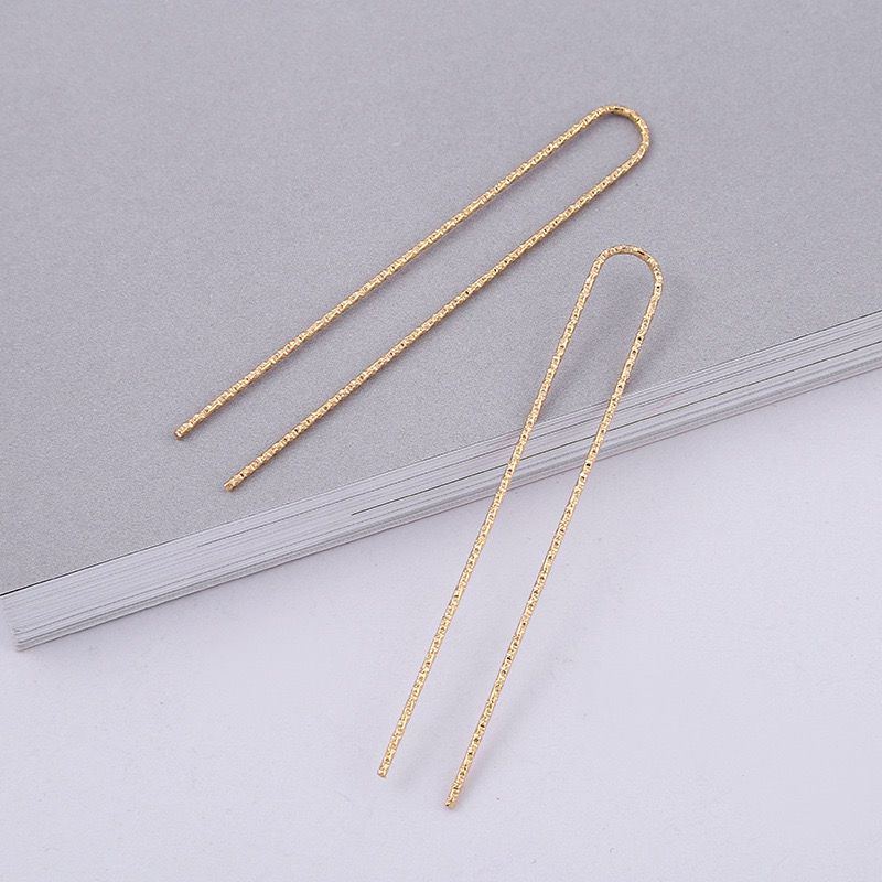 Close-up view of two gold alloy U-shaped hair sticks, ideal as a base for crafting or for minimalist hair buns.