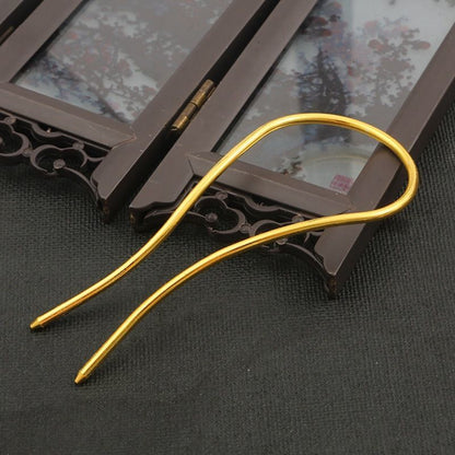 Side profile of a gold alloy arched hair fork, demonstrating its sturdy construction for holding updos.