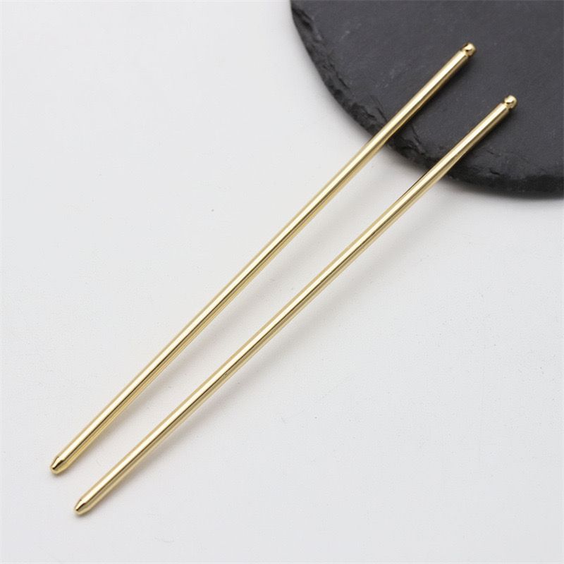 A pair of polished gold metal hair sticks designed for crafting or minimalist hairstyles.