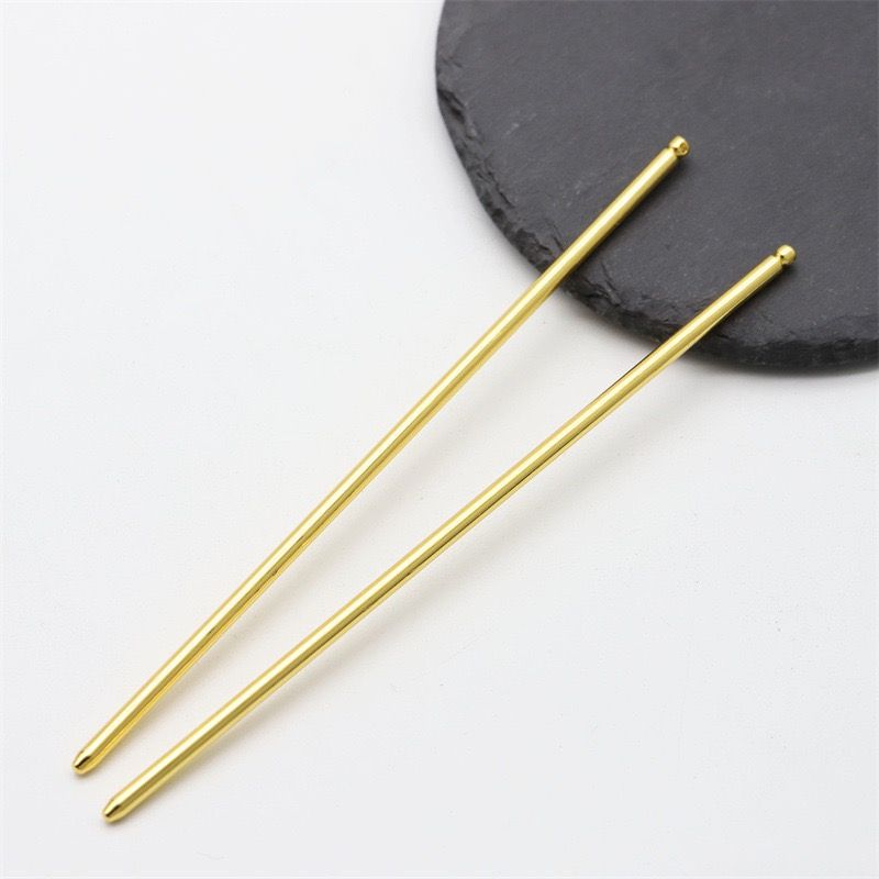 Close-up view of two gold ball tip hair sticks, showcasing their sleek, high-quality finish.