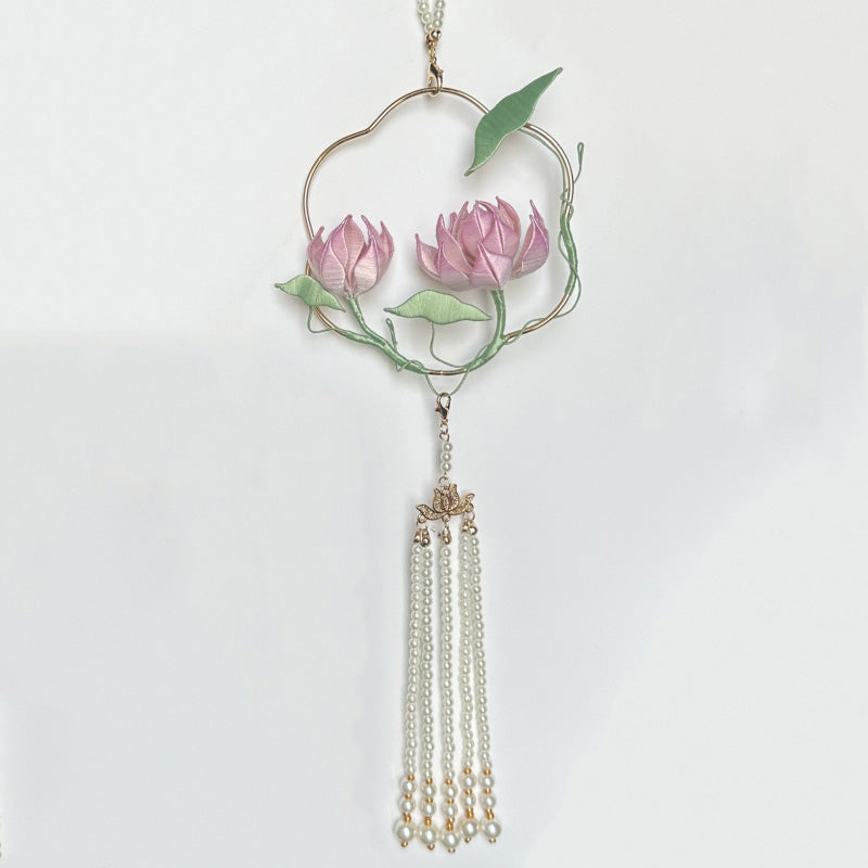 An elegant Chanhua hanging wall ornament featuring two pink lotus flowers and green leaves inside a decorative metal frame with pearl tassels.