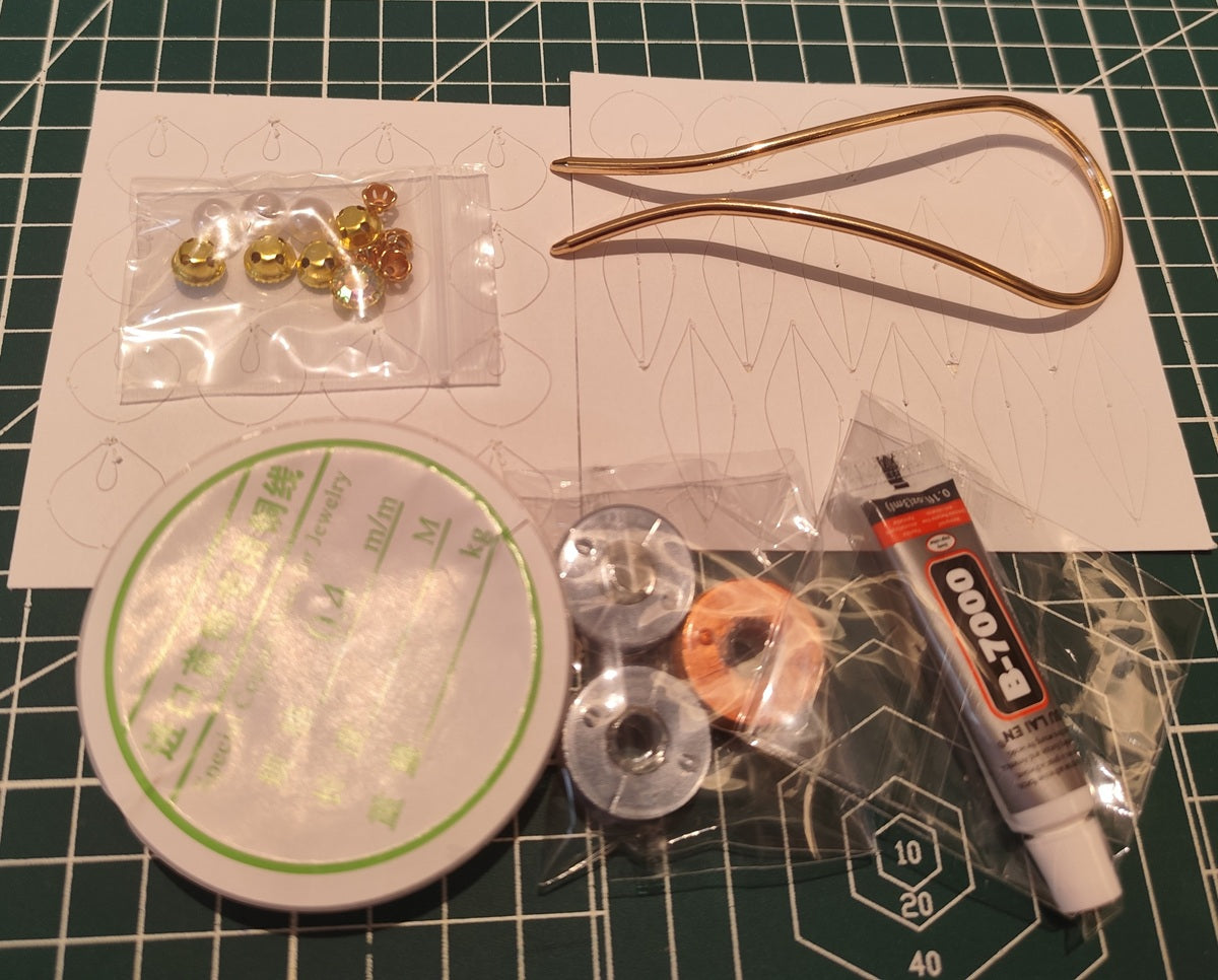 DIY flower hairpin kit materials, including thread spools, beads, glue, and a gold hair fork base.