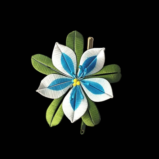Luxury 3D embroidery floral pin depicting a white and blue flower made with intricate artisanal thread-wrapping techniques.