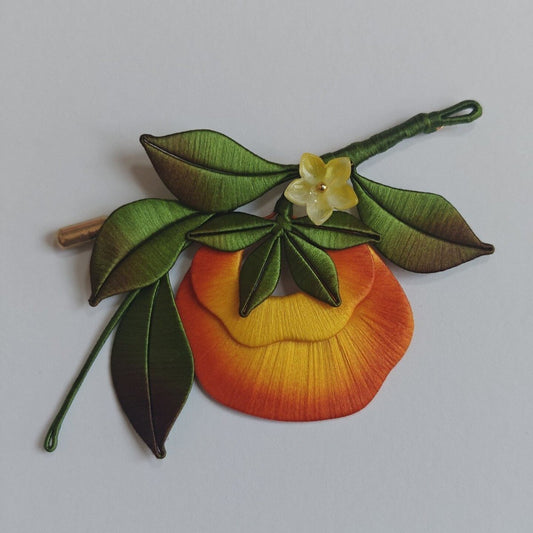 Luxury 3D embroidery fruit pin depicting a ripe persimmon made with intricate artisanal thread-wrapping techniques.