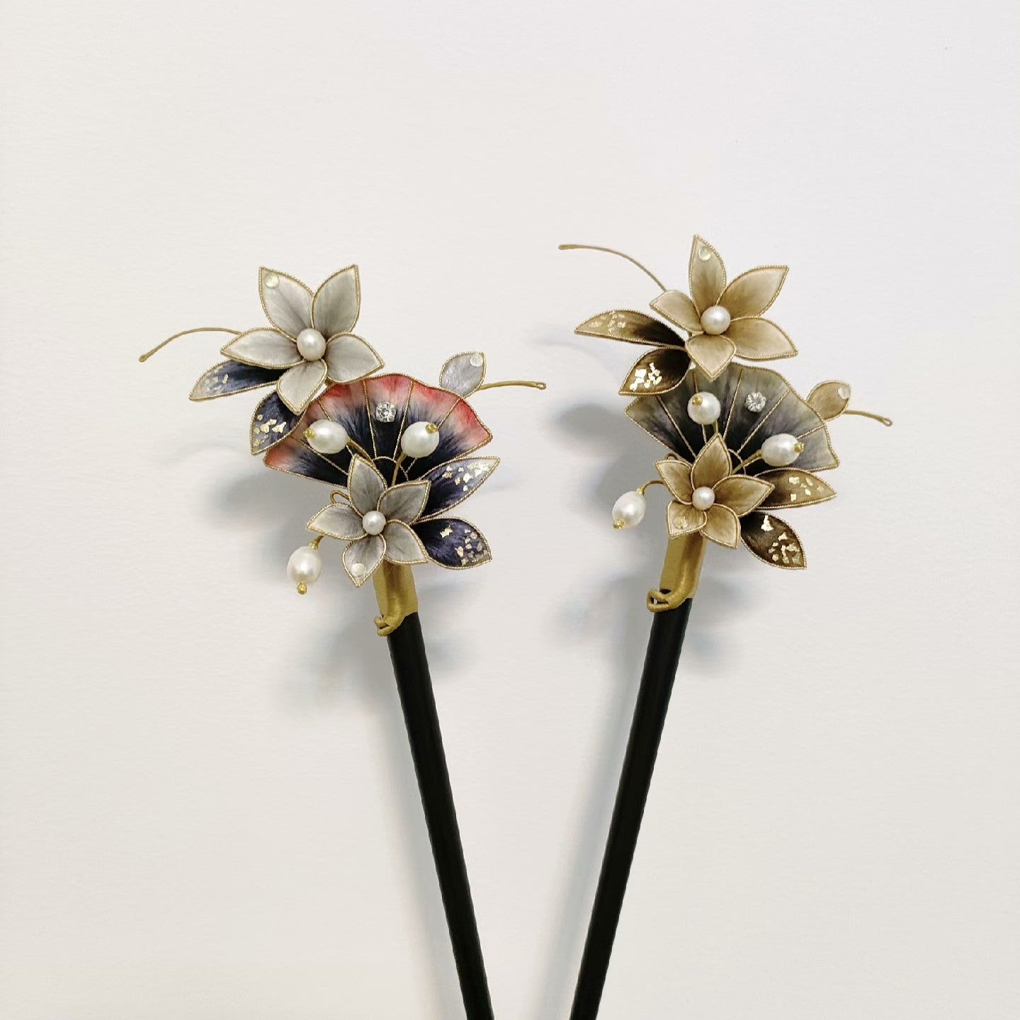Ronghua handmade ink wash flower hairpins in two styles — gold and grey, and ink blue and pink — each with pearl centers, gold wire accents, and long pearl tassel drop, held in hand against a white background