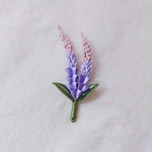Chanhua handmade sage brooch with purple and pink ombre flower spikes and green leaves, displayed on white fabric