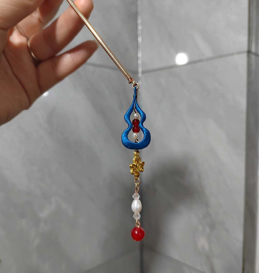 Handheld view of an intricate Chanhua thread-wrapped hair accessory featuring blue spiral patterns and red gemstone accents.