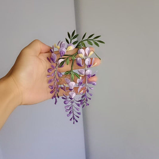 A top-down, slightly high-angle view showing the intricate details of a handmade silk-thread (Chanhua) wisteria trailing floral art piece against a plain background.