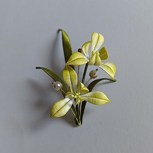 Luxury 3D embroidery floral pin depicting a blooming orchid made with intricate artisanal thread-wrapping techniques.