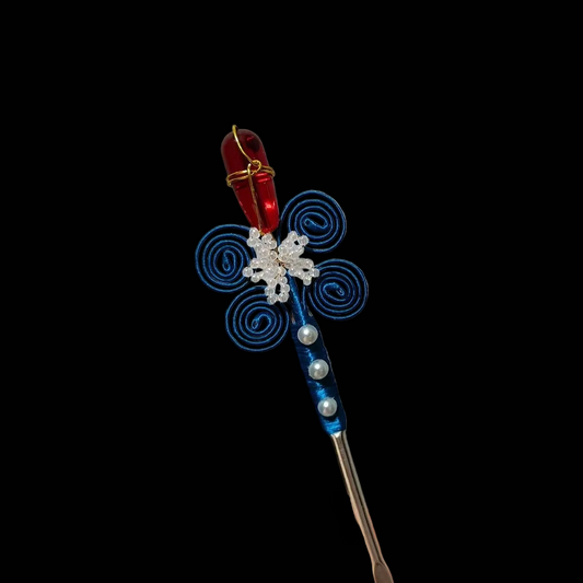 Handheld view of a handcrafted Chanhua thread-wrapped hairpin featuring a red flower bud and blue spiral patterns with pearl accents.