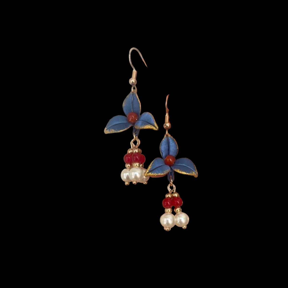 Handheld view of a pair of handmade Chanhua thread-wrapped earrings featuring vintage blue petals with gold edges, red beads, and pearl drops.
