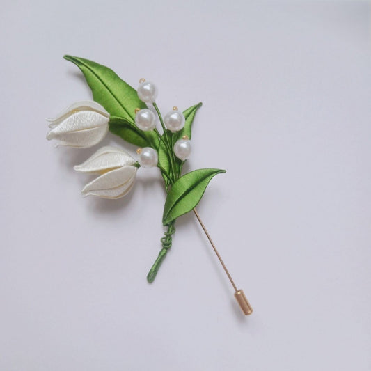 3D floral pin depicting a blooming Lily of the Valley made with intricate traditional thread-wrapping techniques.