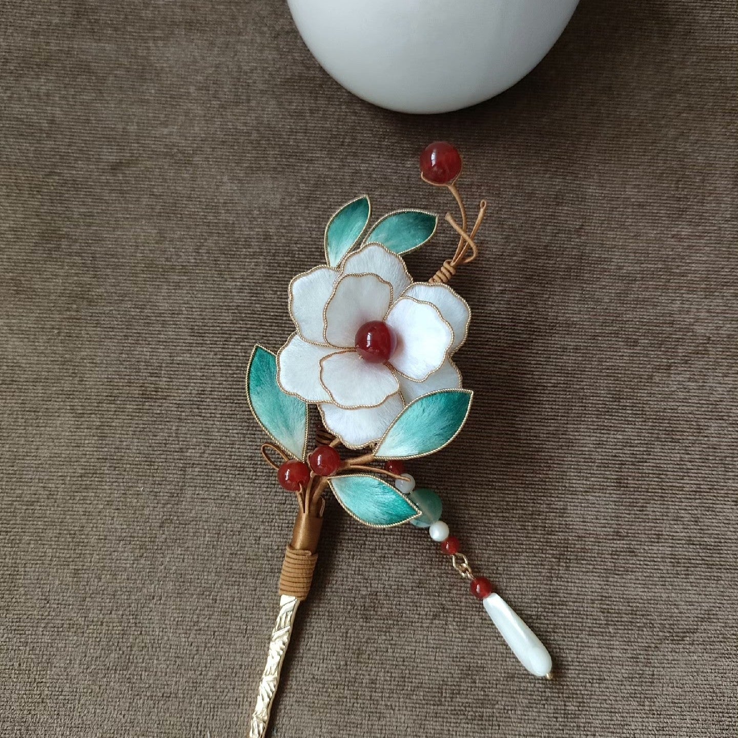 Close-up of delicate white camellia Ronghua velvet petals and gold accents on traditional Chinese hairpin