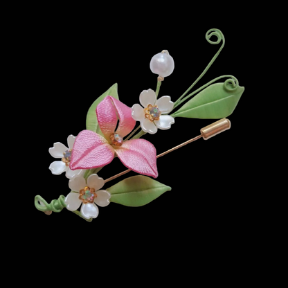 Handcrafted Chanhua pink flower brooch featuring thread-wrapped petals, golden stamens, and green leaves.