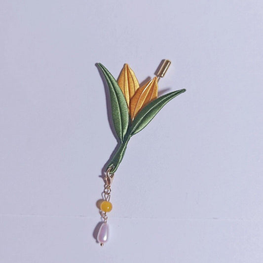 Chanhua handmade corn brooch with golden yellow bud, green leaves, and a pearl drop on a gold chain, displayed on a light gray background