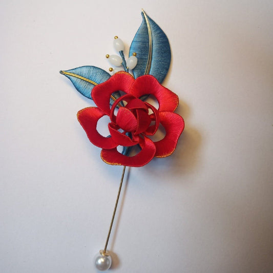 3D floral pin depicting a blooming red rose made with traditional artisanal thread-wrapping techniques.