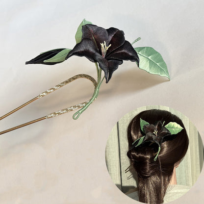 Black Chanhua datura flower hairpin, worn in a bun, with an antique gold-tone hairpin base.