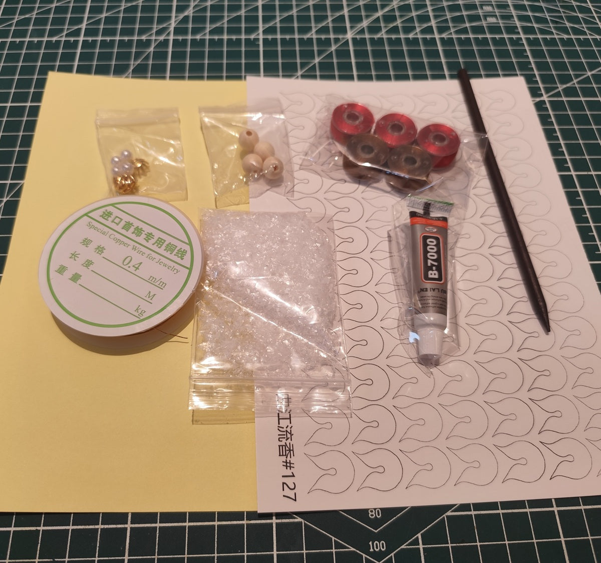 DIY flower craft supplies including red and brown threads, copper wire, glue, beads, paper templates, and artificial snow powder for a plum blossom hairpin.