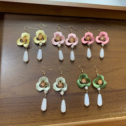 Collection of handmade Chanhua flower earrings in various soft colors on a white fabric background.