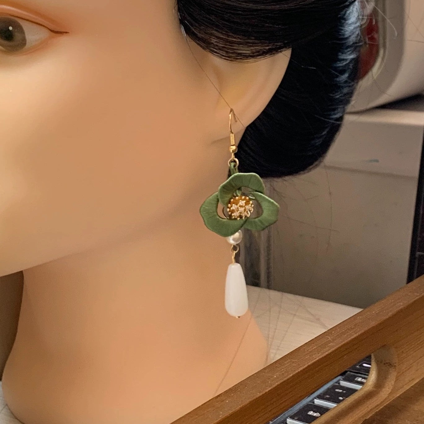 Handmade Chanhua flower earrings in a delicate green color, shown on a mannequin.