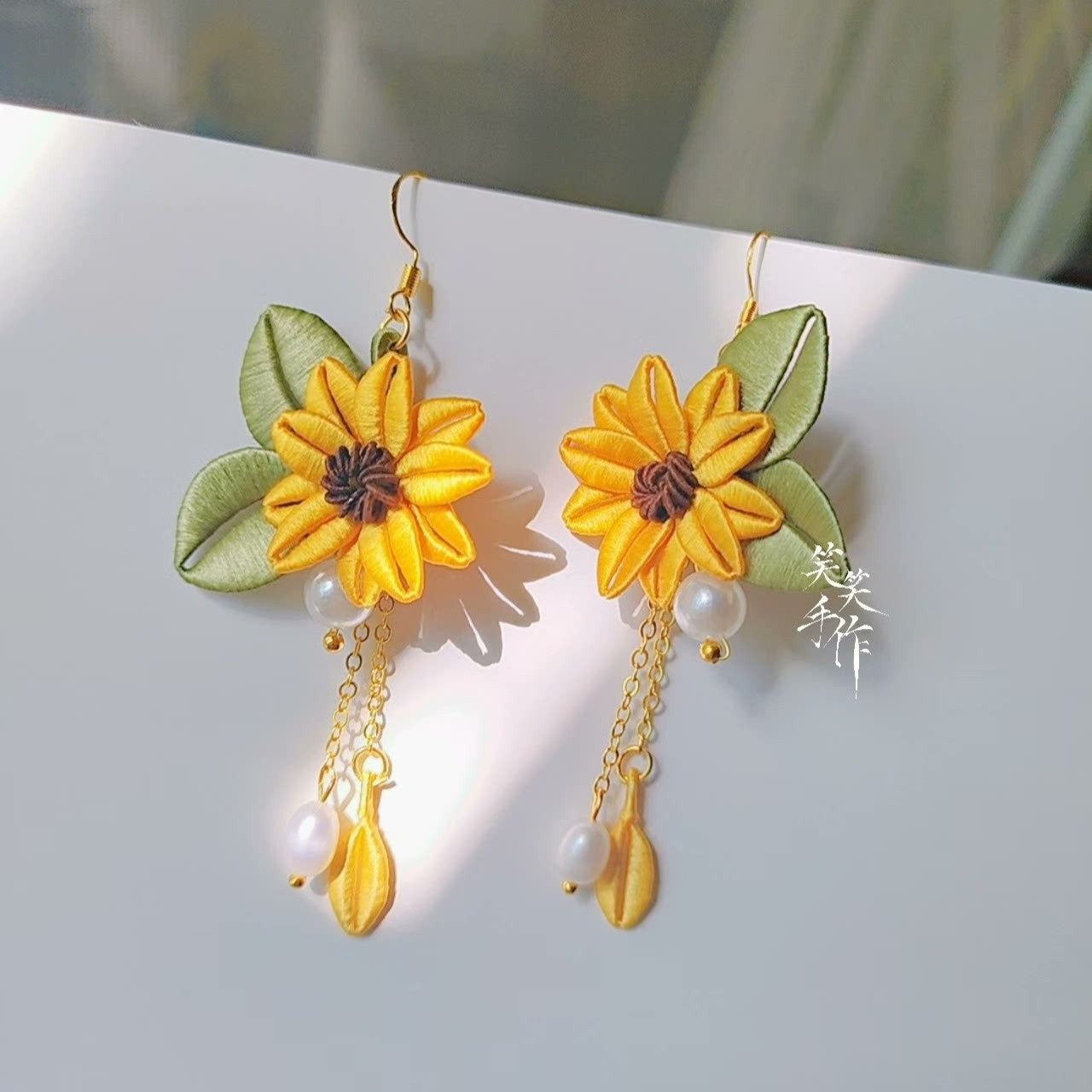 Vibrant handcrafted Chanhua sunflower-style earrings with yellow petals, green leaves, and unique yellow bead and pearl drops, showcasing artisan quality.