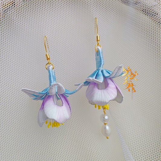 Close-up shot of the handmade Chanhua flower earrings, highlighting the natural freshwater pearls dangling from one earring and the vibrant yellow stamens, demonstrating the quality of materials and craftsmanship.