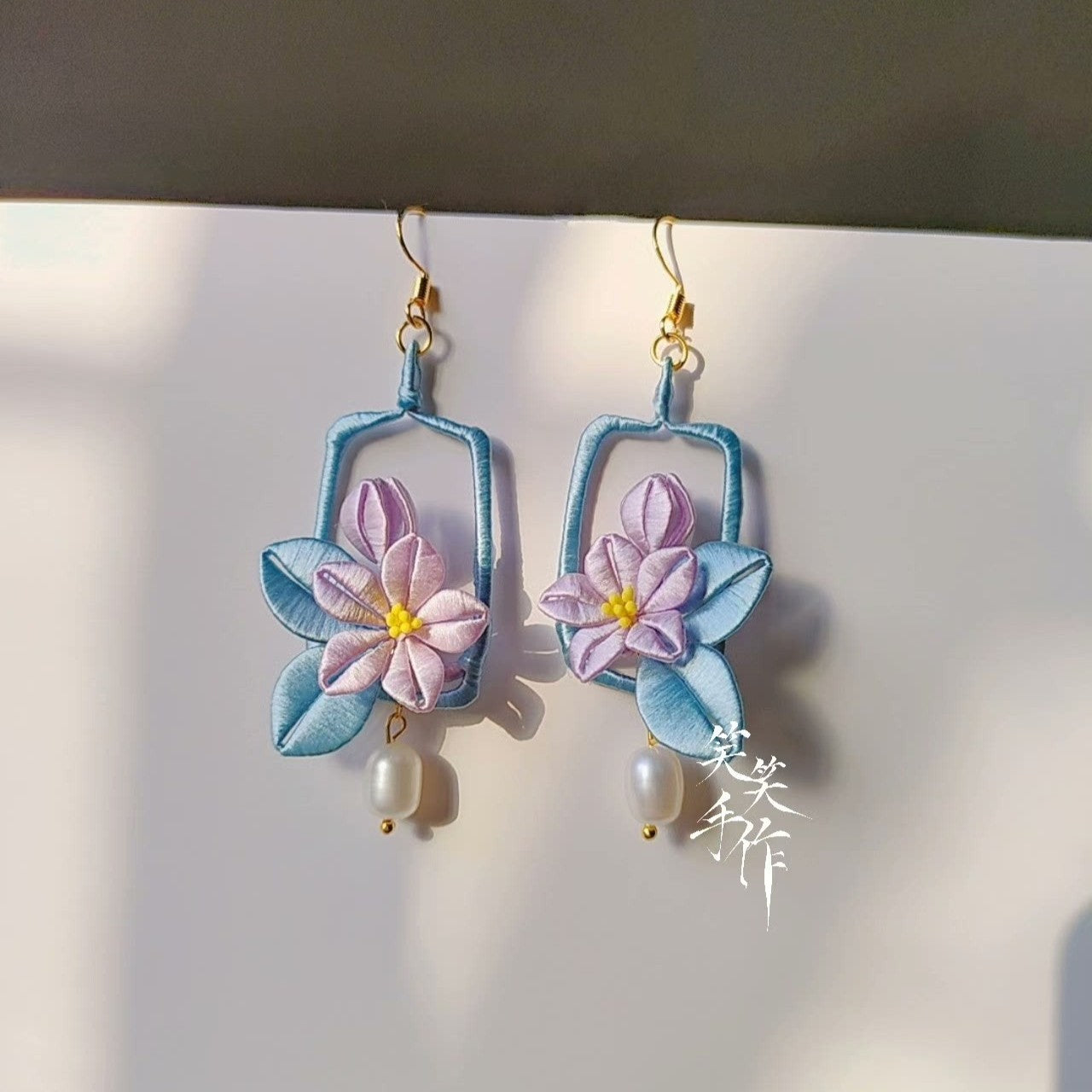 Close-up shot of the handmade Chanhua flower earrings, highlighting the intricate textile craftsmanship, 925 silver hooks, and lustrous white freshwater pearls.