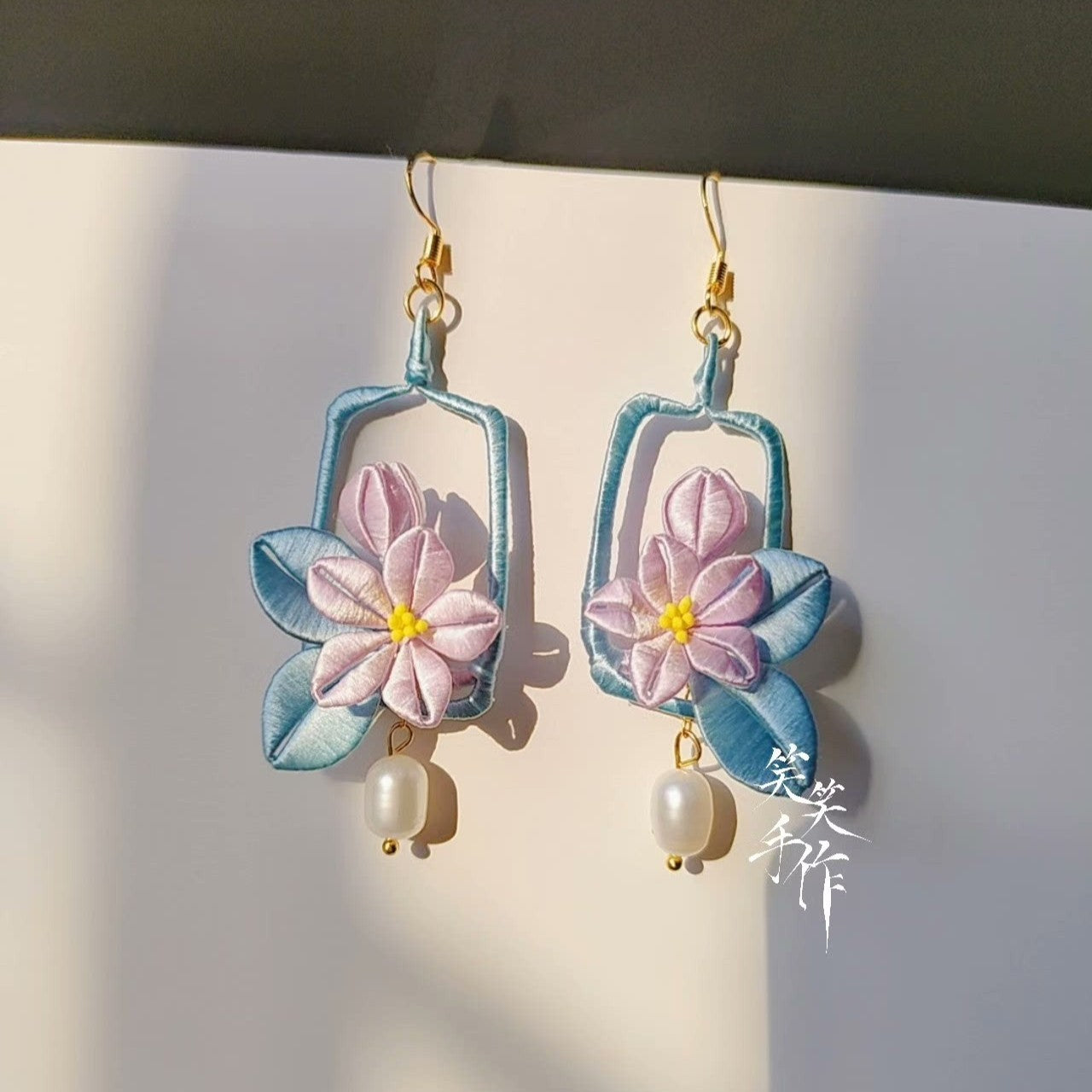 View of the elegant Chanhua earrings, showing their light blue frame design and the delicate interplay of pastel colors, perfect for special occasions.