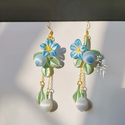 Pair of artisan Chanhua floral earrings featuring delicate embroidery and genuine freshwater pearls, casting soft shadows.